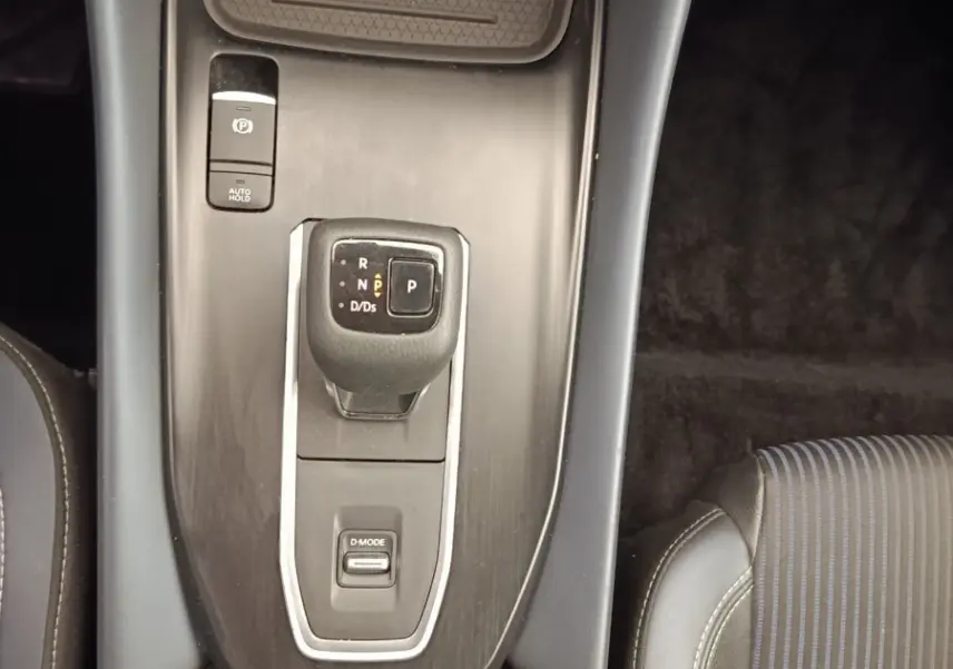Vue plongeante sur la console centrale noire du Nissan Qashqai 2023, avec levier de vitesses automatique et porte-gobelets.