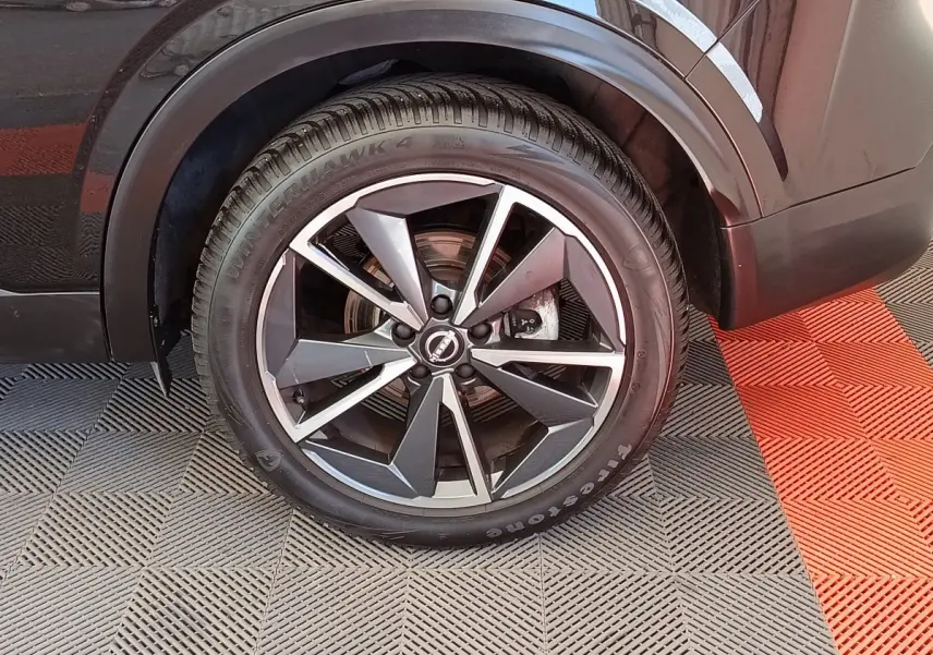 Gros plan sur la roue arrière droite noire du Nissan Qashqai 1.3 MHEV 158ch Xtronic Tekna avec jante alliage moderne.
