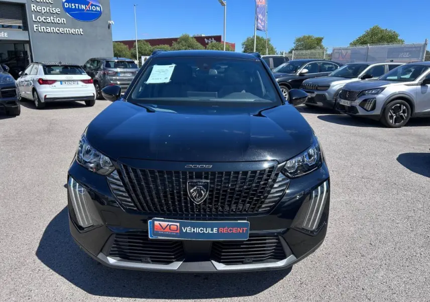Vue avant d'un Peugeot 2008 Hybrid noir 2025 avec calandre distinctive et barres de toit visibles en extérieur.