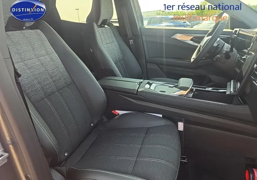 Vue intérieure côté conducteur du Renault Austral 2025 avec sièges tissu noir et accoudoir central cuir.