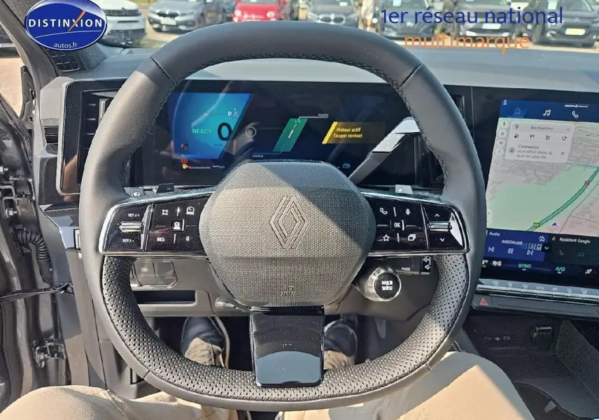 Vue intérieure centrée sur le volant multifonction noir du Renault Austral gris schiste avec écrans numériques en arrière-plan.