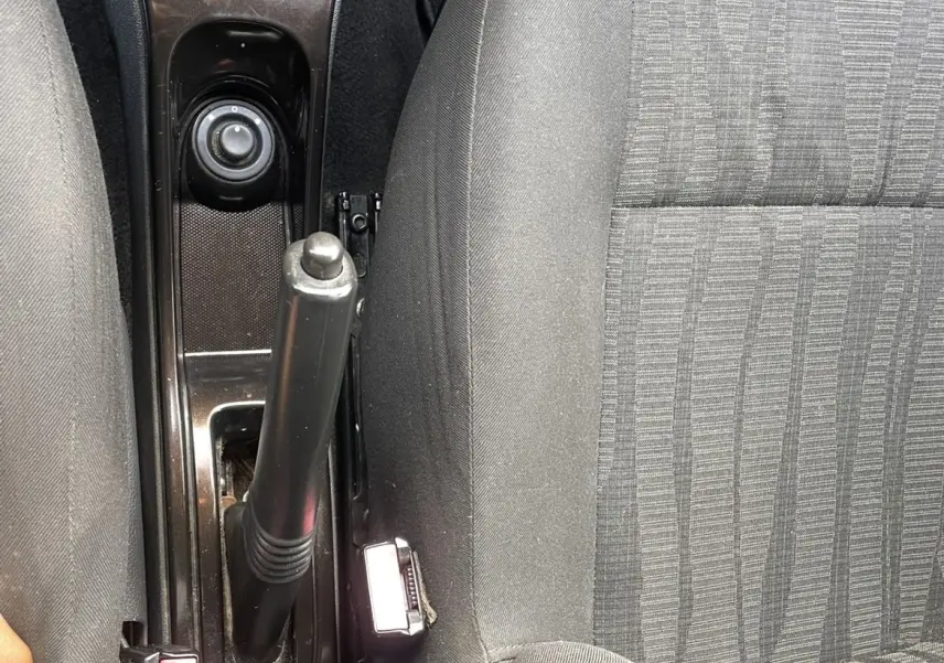 Vue rapprochée de la console centrale et des sièges avant gris du Dacia Duster 2011 avec frein à main manuel et levier de vitesses.