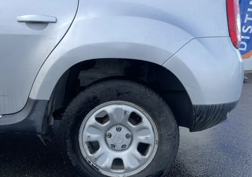 Dacia Duster gris vue du côté arrière droit, mettant en valeur la roue arrière avec enjoliveur et la vitre teintée.