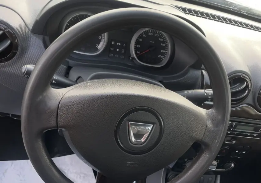 Vue intérieure centrée sur le volant et le tableau de bord du Dacia Duster 2011, avec levier de vitesse manuel visible.