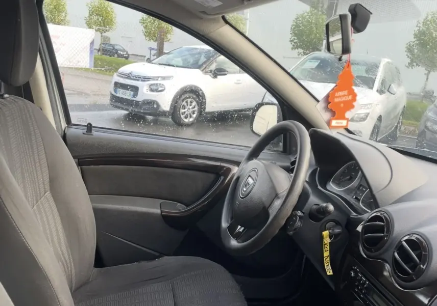 Vue intérieure côté conducteur du Dacia Duster gris 2011 avec volant, levier de vitesse manuel et tableau de bord visible.