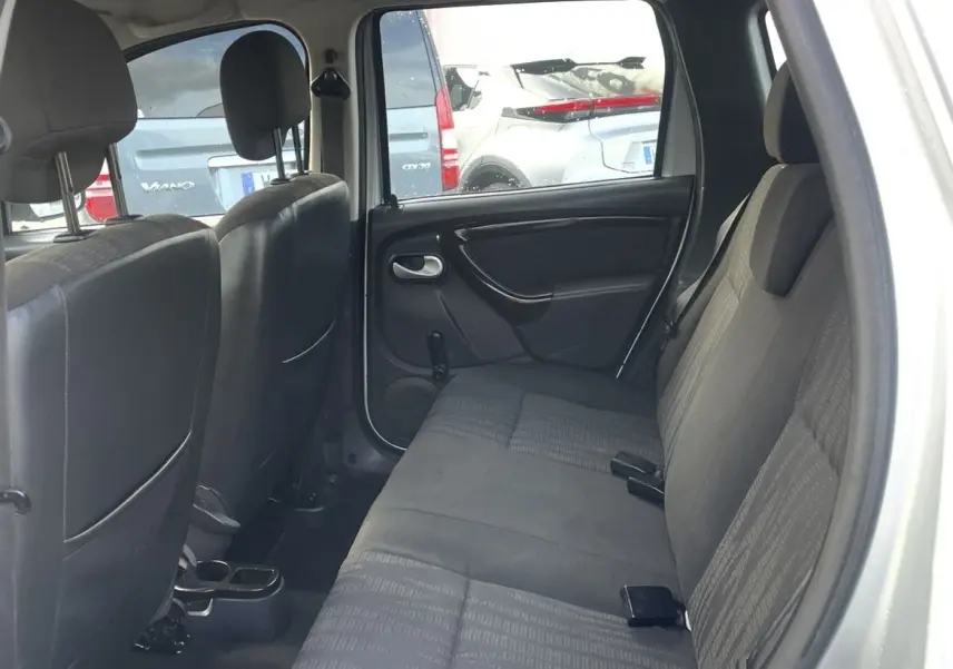 Vue intérieure arrière droite du Dacia Duster gris montrant la banquette 1/3-2/3 et les sièges en tissu noir.
