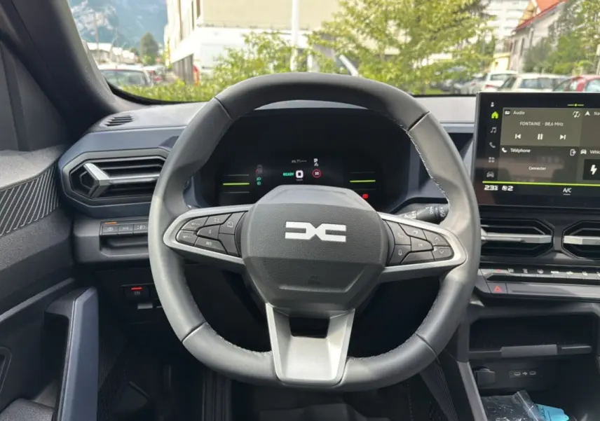 Vue intérieure centrée sur le volant cuir du Dacia Duster 2026, avec tableau de bord numérique et écran tactile central.