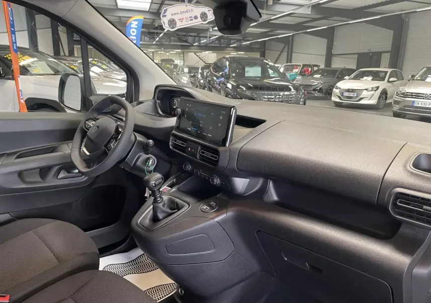 Vue intérieure côté conducteur du Peugeot Partner 2026, montrant tableau de bord noir avec écran tactile et boîte manuelle.