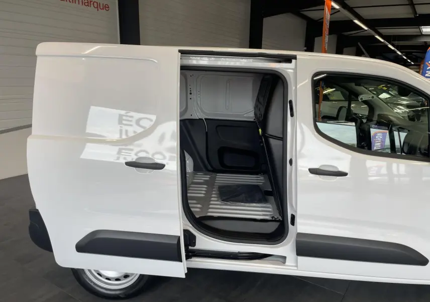 Vue latérale droite d’un Peugeot Partner blanc avec porte coulissante ouverte montrant l’espace de chargement vide.