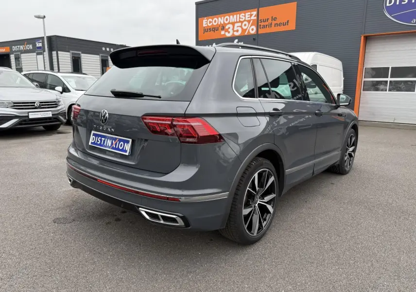 Vue 3/4 arrière droite d'un Volkswagen Tiguan gris dauphin avec jantes alliage 20 pouces et double sortie d'échappement.