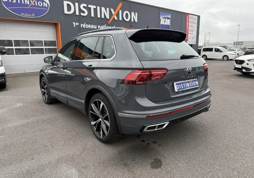 Vue 3/4 arrière droite d'un Volkswagen Tiguan gris dauphin avec jantes alliage 20 pouces sur parking extérieur.
