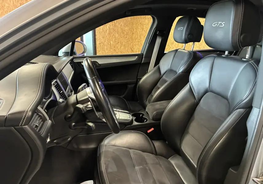 Vue intérieure côté conducteur du Porsche Macan GTS 2017, sièges cuir noirs avec logo GTS brodé sur appuis-tête.