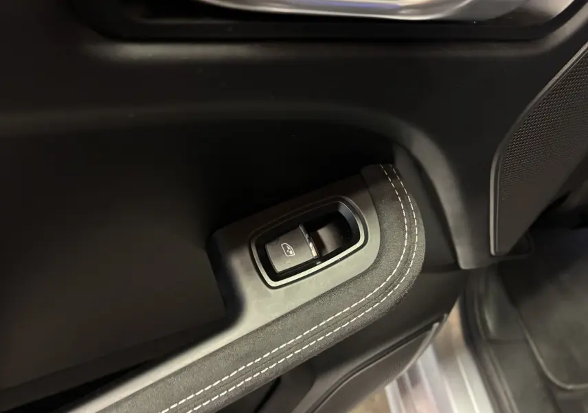 Gros plan sur le bouton de commande de lève-vitre noir avec surpiqûres blanches sur la garniture intérieure du côté conducteur du Porsche Macan GTS 2017.