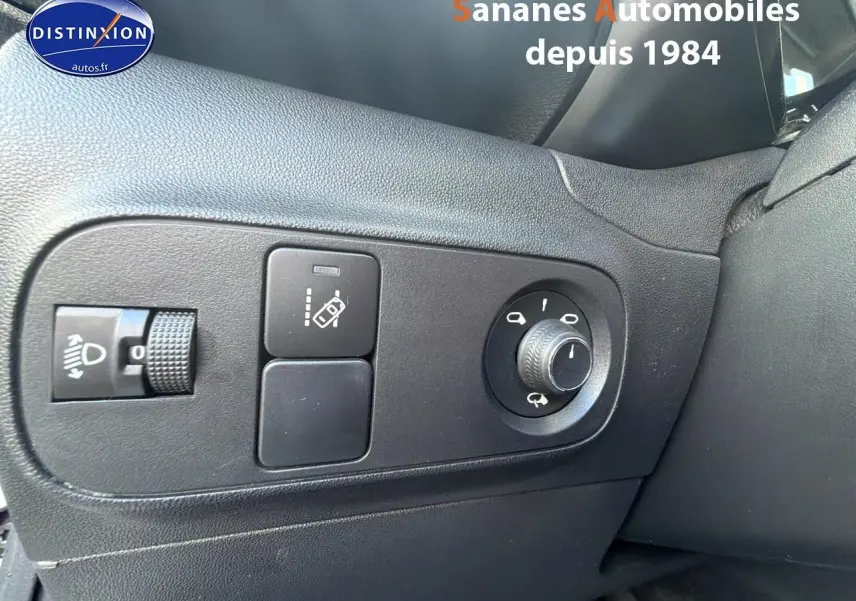 Gros plan sur les commandes de réglage des rétroviseurs et des phares à gauche du volant dans une Citroën C3 blanche 2018.