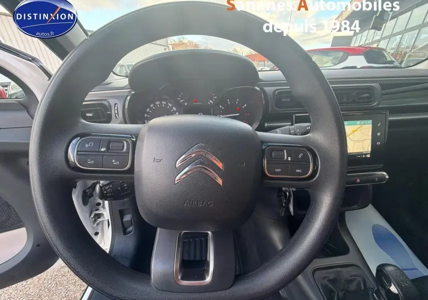 Vue intérieure centrée sur le volant de la Citroën C3 blanche de 2018 avec tableau de bord et écran tactile visible.