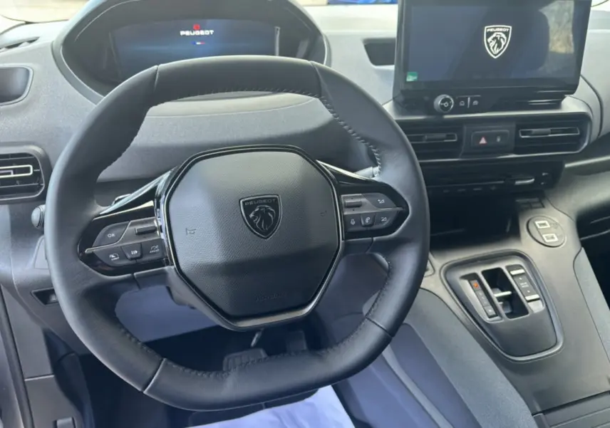 Vue intérieure centrée sur le volant cuir multifonctions et l’écran tactile du Peugeot Rifter gris Artense 2026.