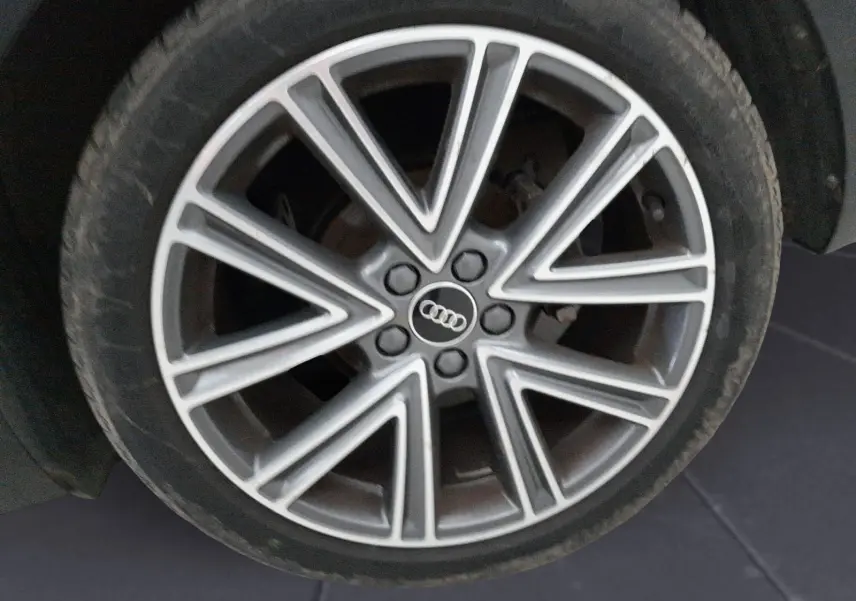 Gros plan sur la jante alliage argentée à design étoilé de l'Audi A1 Sportback noire, roue avant droite.