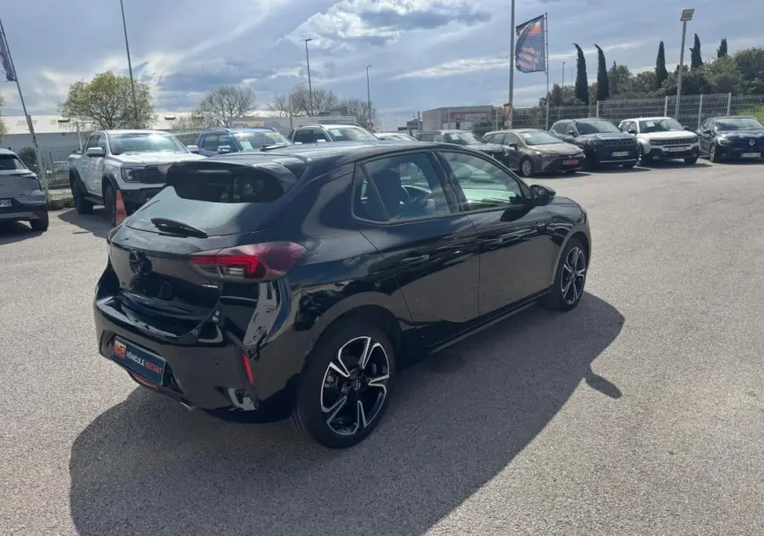 Opel Corsa noire vue 3/4 arrière droit, avec jantes alliage 17 pouces, stationnée en extérieur sous ciel nuageux.
