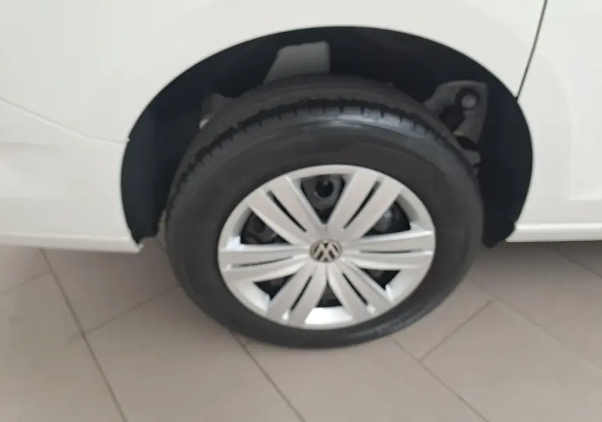 Gros plan sur la roue avant droite d’un Volkswagen Caddy Cargo Maxi blanc Candy, avec jante argentée et logo VW central.