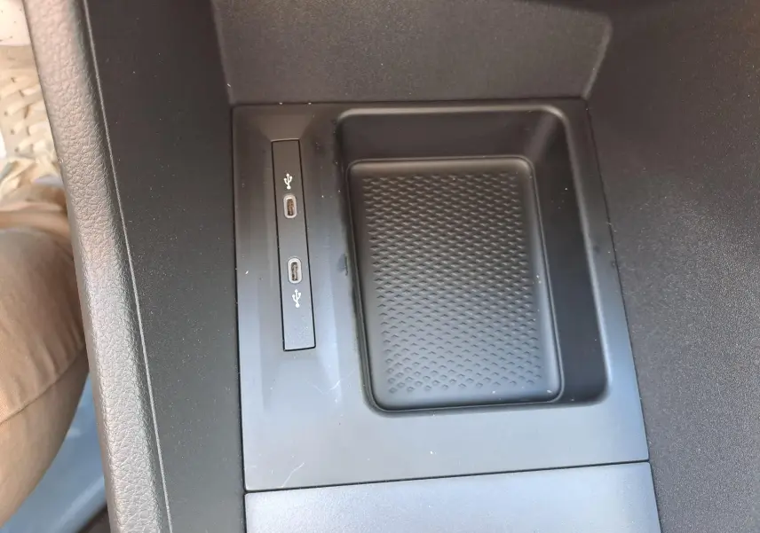 Gros plan sur la console centrale noire du Volkswagen Caddy Cargo Maxi 2026 avec deux ports USB-C et un espace de rangement.