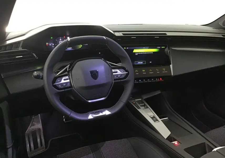 Intérieur de la Peugeot 308 2025 vue de face, tableau de bord moderne avec volant compact et écran tactile central.
