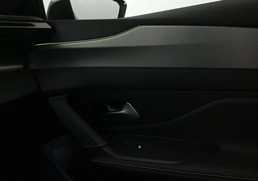 Détail de la porte côté gauche de la Peugeot 308 blanche, avec éclairage d'ambiance vert et garniture noire élégante.
