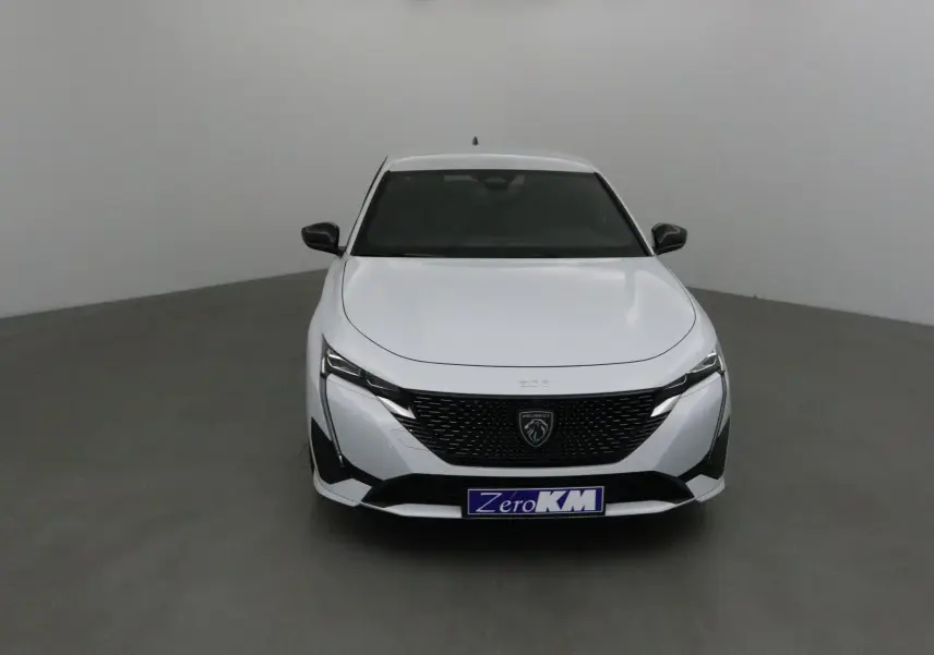 Vue frontale d'une Peugeot 308 blanche Okenite avec calandre noire et logo lion central bien visible.