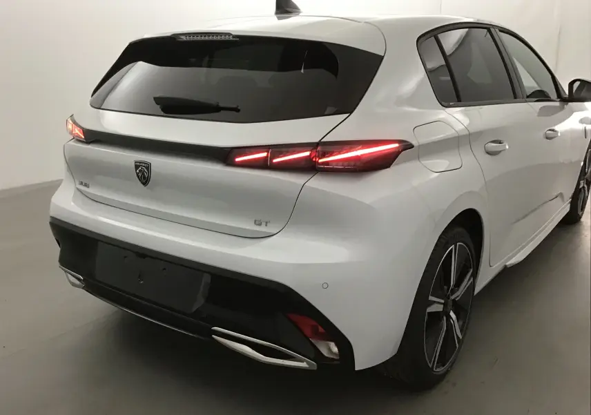 Vue 3/4 arrière droite d'une Peugeot 308 GT blanche Okenite avec feux arrière LED allumés et jantes alliage noires.