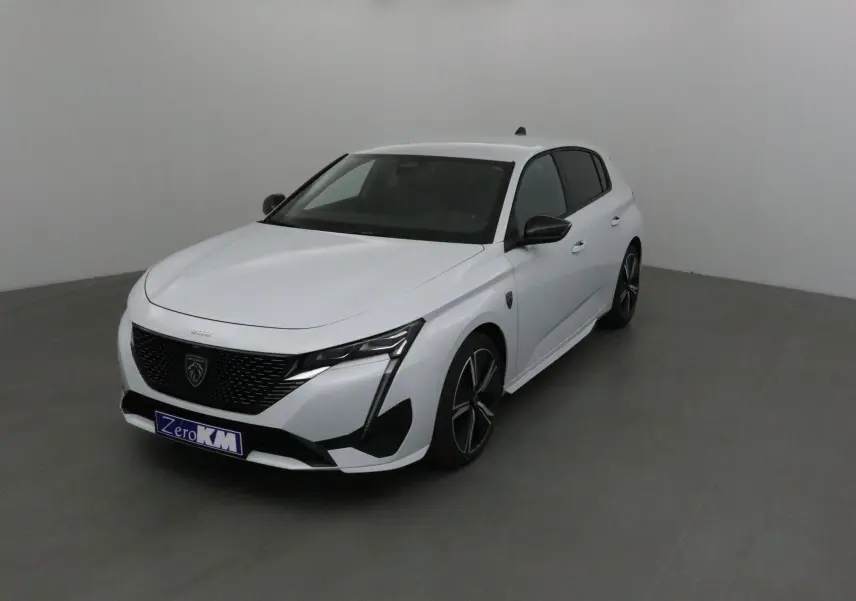 Vue 3/4 avant droite d'une Peugeot 308 blanche Okenite avec jantes noires et calandre noire distinctive.