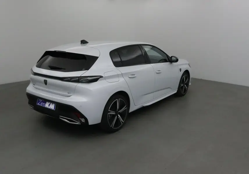 Peugeot 308 GT blanc Okenite vue 3/4 arrière droit dans un studio, avec jantes alliage et vitres teintées.