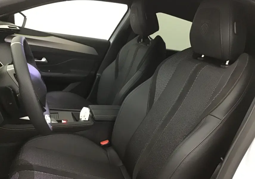 Intérieur avant de la Peugeot 308 GT+Pack Alcantara 2025, sièges noirs en cuir et Alcantara avec logo Peugeot brodé.