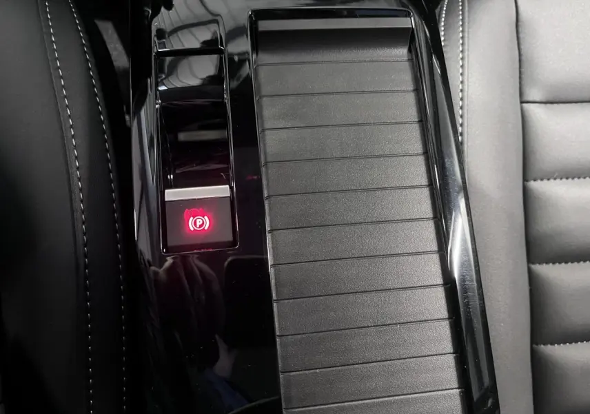 Gros plan sur la console centrale noire brillante de la Citroën C4 2025 avec bouton de frein de stationnement électrique allumé.
