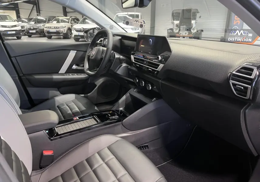 Intérieur avant droit de la Citroën C4 2025 hybride, sièges Advanced Comfort noirs et tableau de bord moderne.