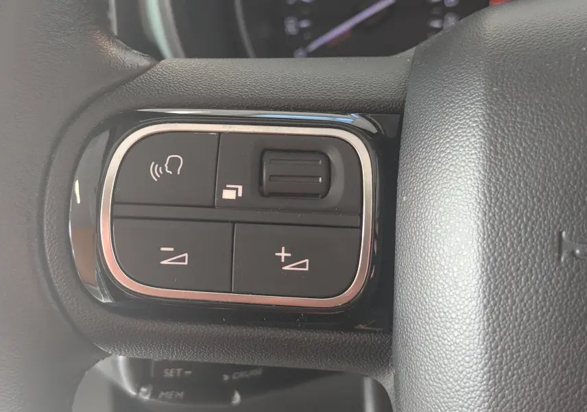 Gros plan sur les commandes de volume et téléphone intégrées au volant du Citroën Berlingo beige 2019.