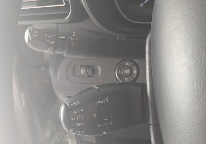 Gros plan sur les commandes au volant du Citroën Berlingo beige 2019, mettant en valeur les boutons de régulateur de vitesse et d'éclairage.