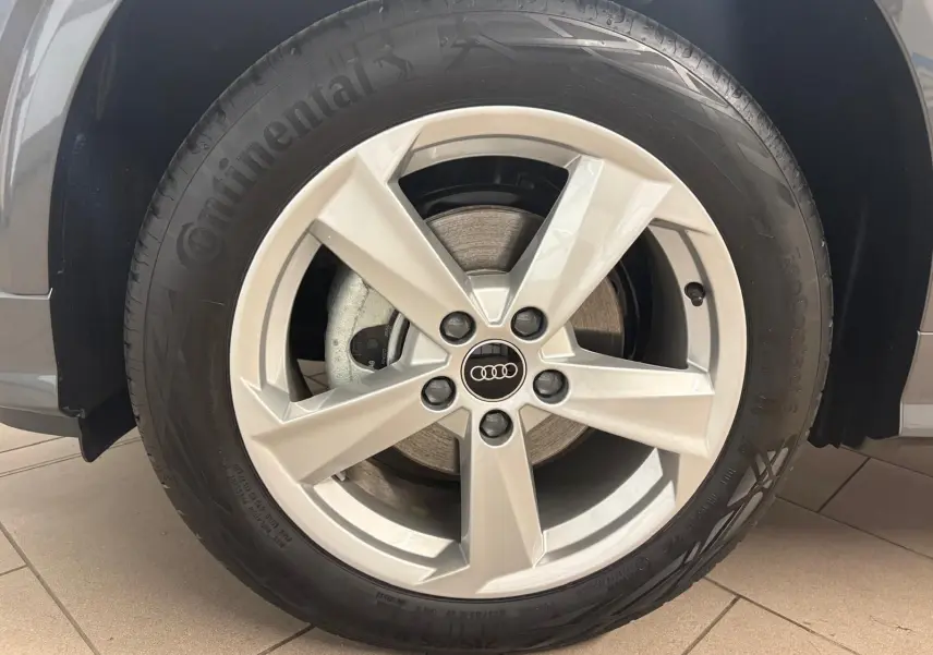 Gros plan sur la roue avant droite de l'Audi Q2 35 TFSI S Line gris Daytona avec jante alliage cinq branches.