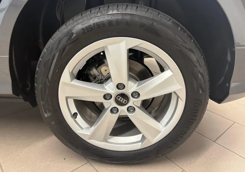 Gros plan sur la roue avant droite de l'Audi Q2 35 TFSI S Line gris Daytona avec jante argentée cinq branches.