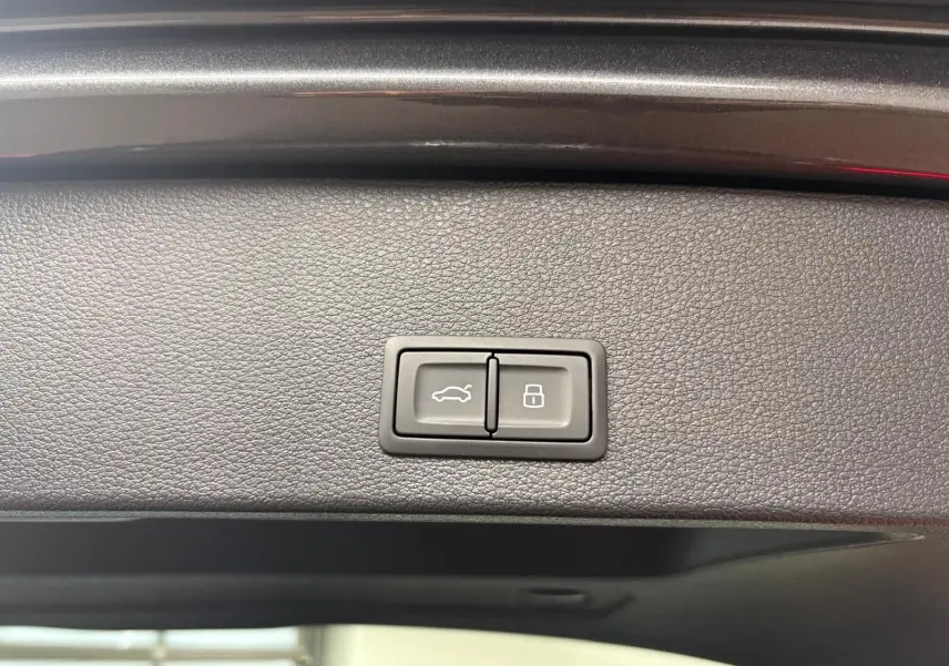 Gros plan sur les boutons du hayon électrique noir à l'intérieur du coffre de l'Audi Q2 Gris Daytona.