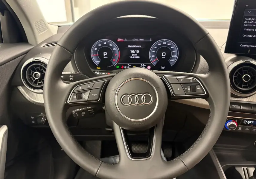 Vue rapprochée du volant et du tableau de bord numérique de l'Audi Q2 35 TFSI S Line, intérieur noir.