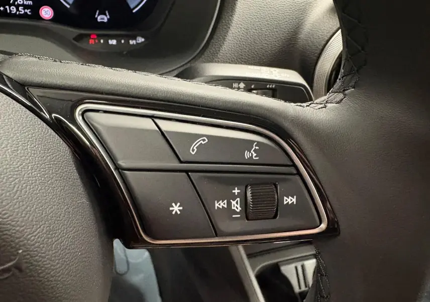 Gros plan sur les commandes au volant noir de l'Audi Q2 35 TFSI S Line 2026 en Gris Daytona.