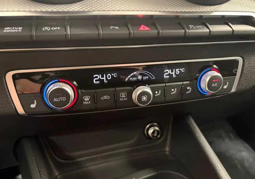 Vue rapprochée du tableau de bord de l'Audi Q2 35 TFSI S Line 2026, montrant la climatisation automatique et les réglages de température.