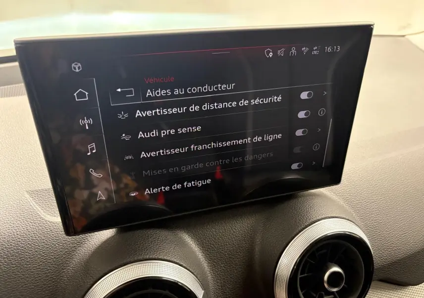 Écran central intérieur de l’Audi Q2 35 TFSI S Line 2026 affichant les aides à la conduite, avec tableau de bord gris.