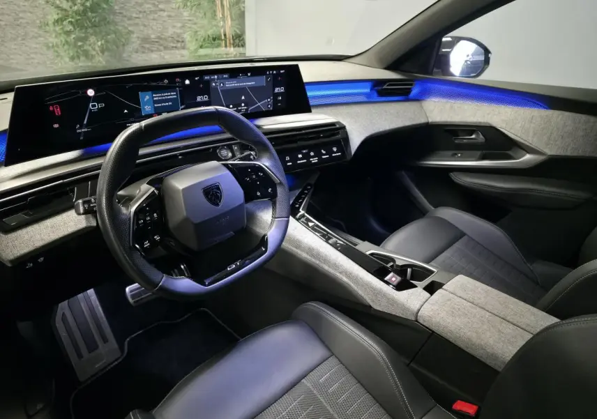 Intérieur Peugeot 3008 2025 vue côté conducteur, tableau de bord numérique panoramique et éclairage d’ambiance bleu.