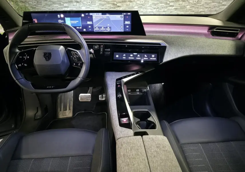 Vue intérieure avant du Peugeot 3008 gris 2025, avec tableau de bord numérique panoramique et éclairage d'ambiance violet.