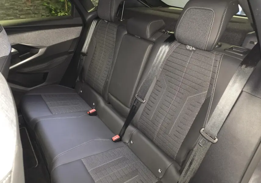 Vue intérieure de la banquette arrière du Peugeot 3008 2025, sellerie tissu noir et gris avec surpiqûres contrastées.