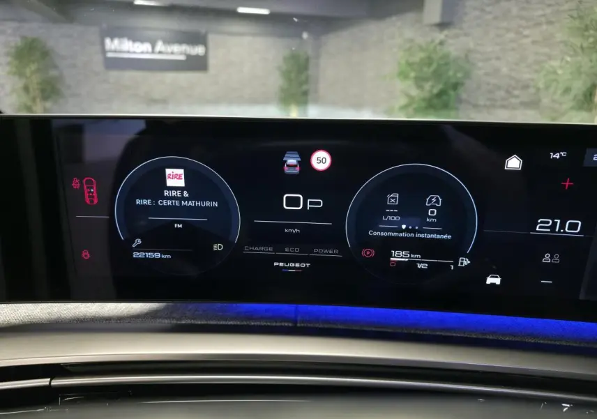 Tableau de bord numérique du Peugeot 3008 hybride 2025 avec affichage connecté et éclairage d’ambiance bleu.
