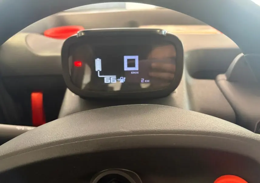 Vue intérieure centrée sur le tableau de bord numérique du Citroën Ami Spicy gris 2025, avec affichage de batterie et compteur.