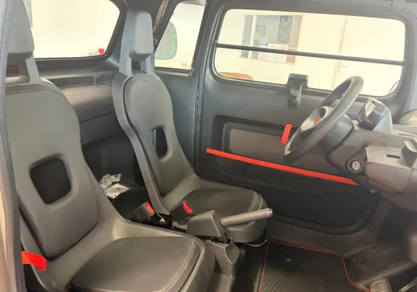 Intérieur de la Citroën Ami Spicy 2025 vu côté droit, sièges gris avec détails rouges et tableau de bord minimaliste.