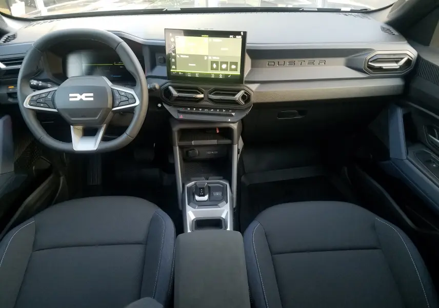 Intérieur avant du Dacia Duster 2025 gris schiste, tableau de bord moderne avec écran tactile central et volant multifonction.
