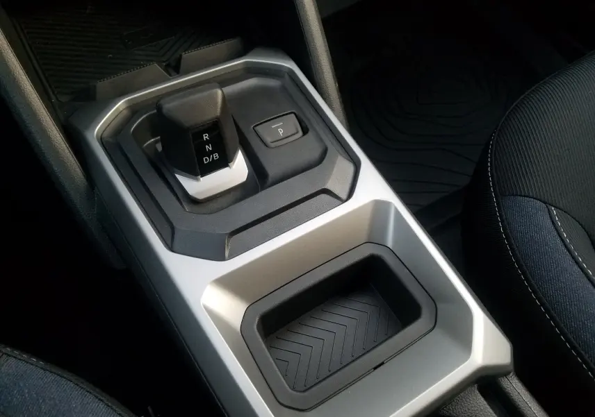 Gros plan sur la console centrale grise du Dacia Duster 2025, mettant en valeur le levier de vitesses automatique et le bouton de parking.